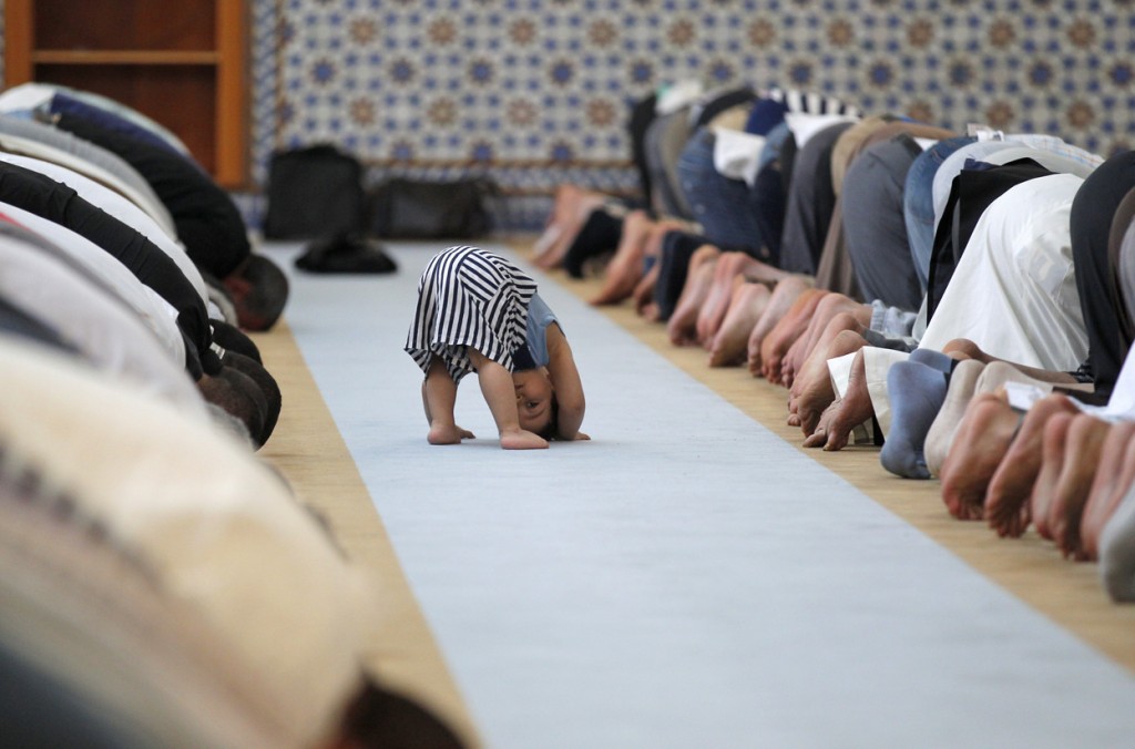 A child leans down near members of the Muslim community attending midday prayers at Strasbourg Grand Mosque in Strasbourg, France, on the first day of Ramadan.