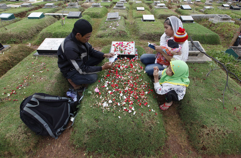 A family reads verses from the Koran at a relative's grave in a cemetery, a day before the Islamic holy month of Ramadan, in Jakarta, on July 9, 2013.