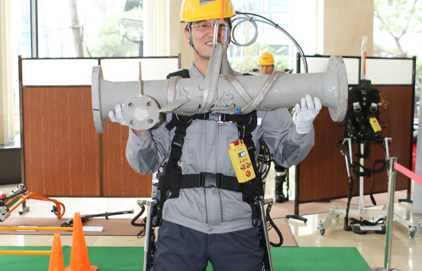 A Daewoo employee poses using the crane extension of the exosuit.